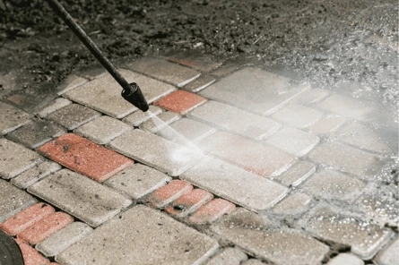 Sierbestrating wordt schoongemaakt met een hogedrukreiniger; vuil en mos worden verwijderd.