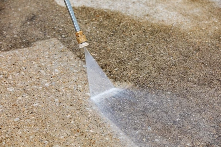 Hogedrukreiniger verwijdert vuil en aanslag van een betonnen oprit.